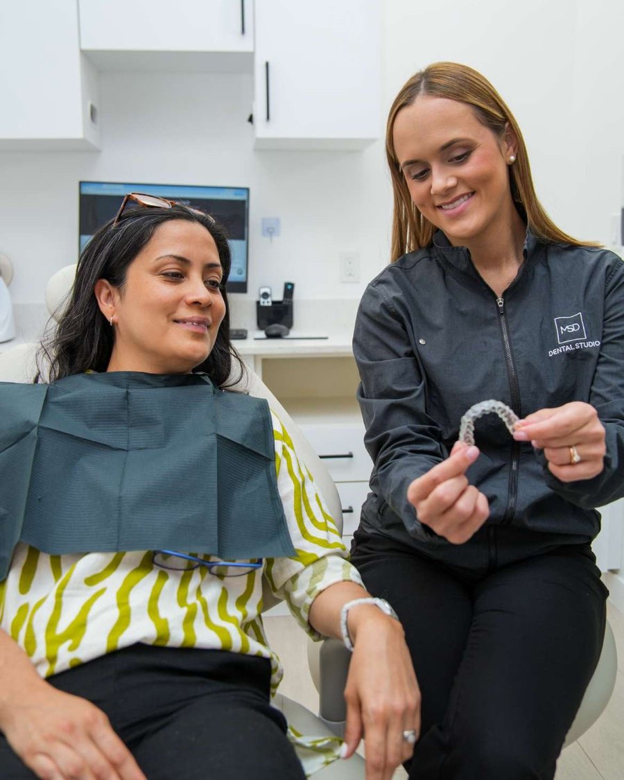 A dentist reviewing a clear aligner with a patient